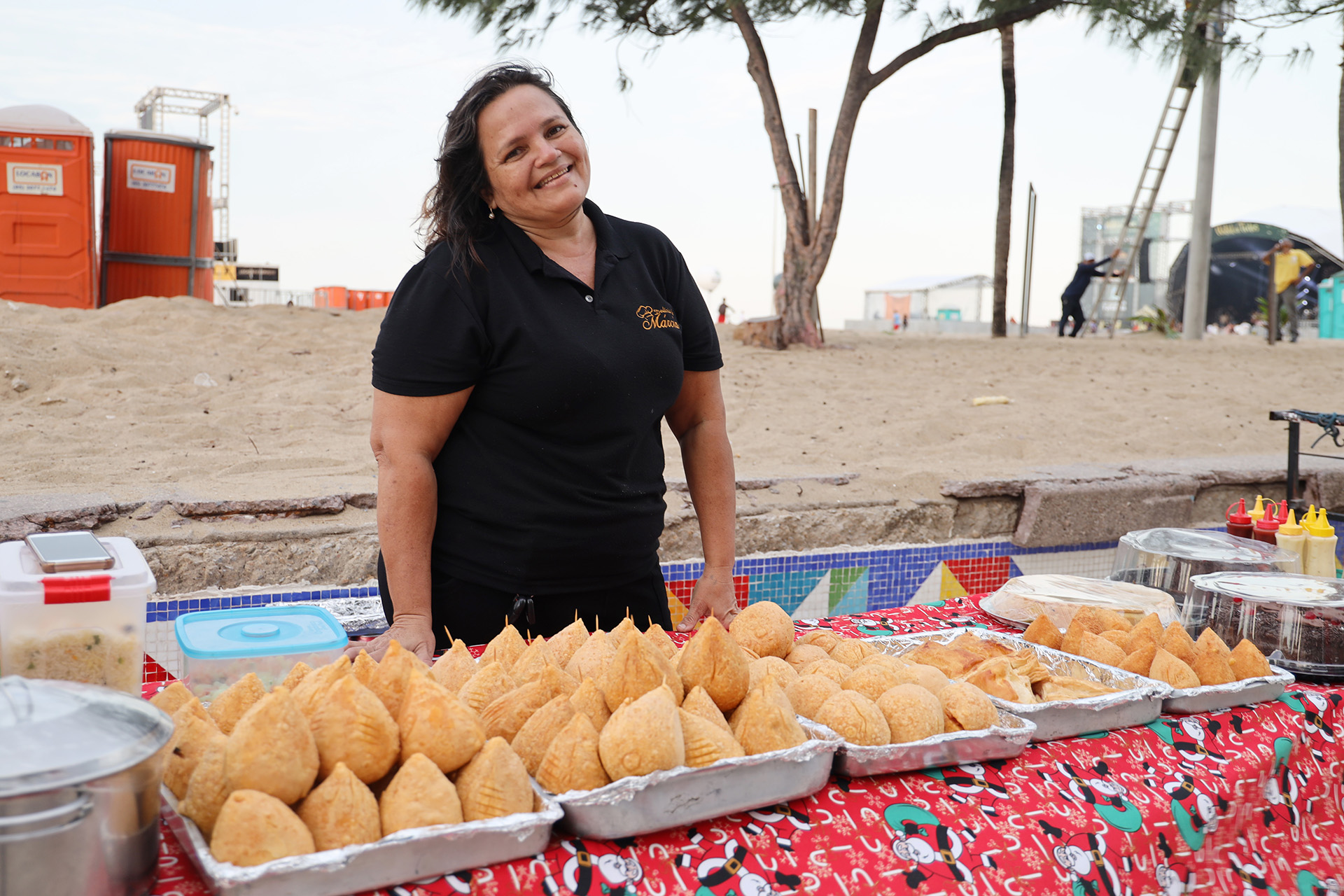 mulher sorrindo atrás de mesa com salgados